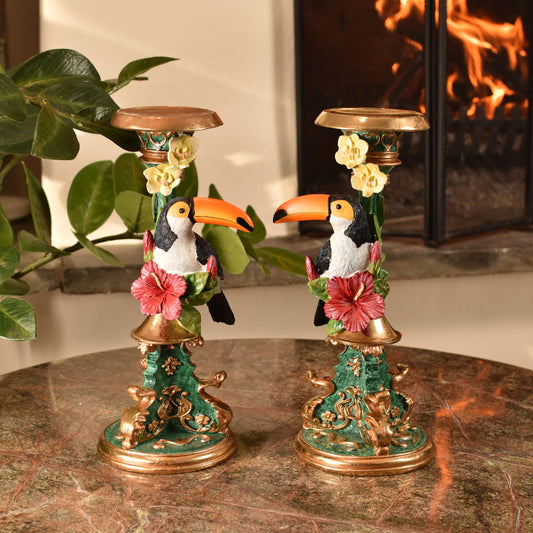 Two decorative candle holders with toucan figures on a marble surface.