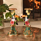 Two decorative candle holders with toucan figures on a marble surface.