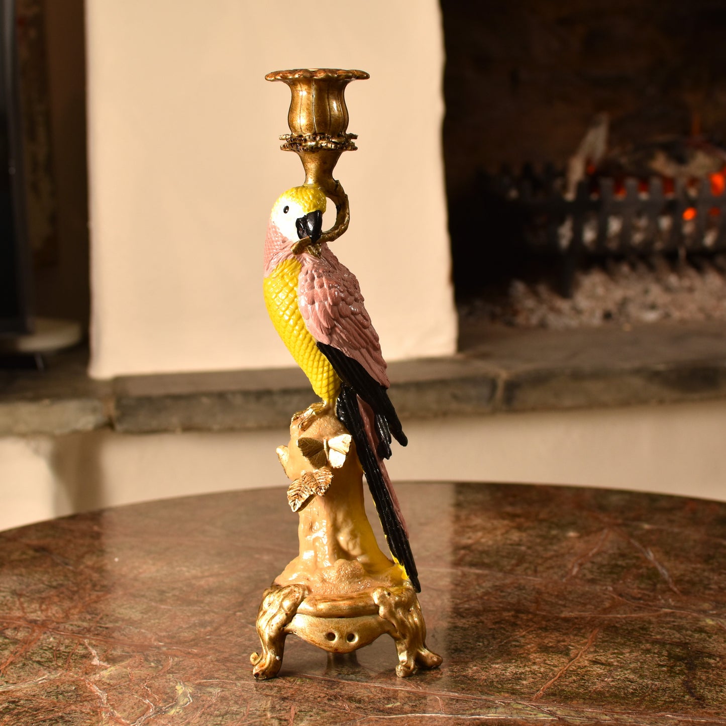 Candle holder shaped like a pink & yellow parrot with a gold base