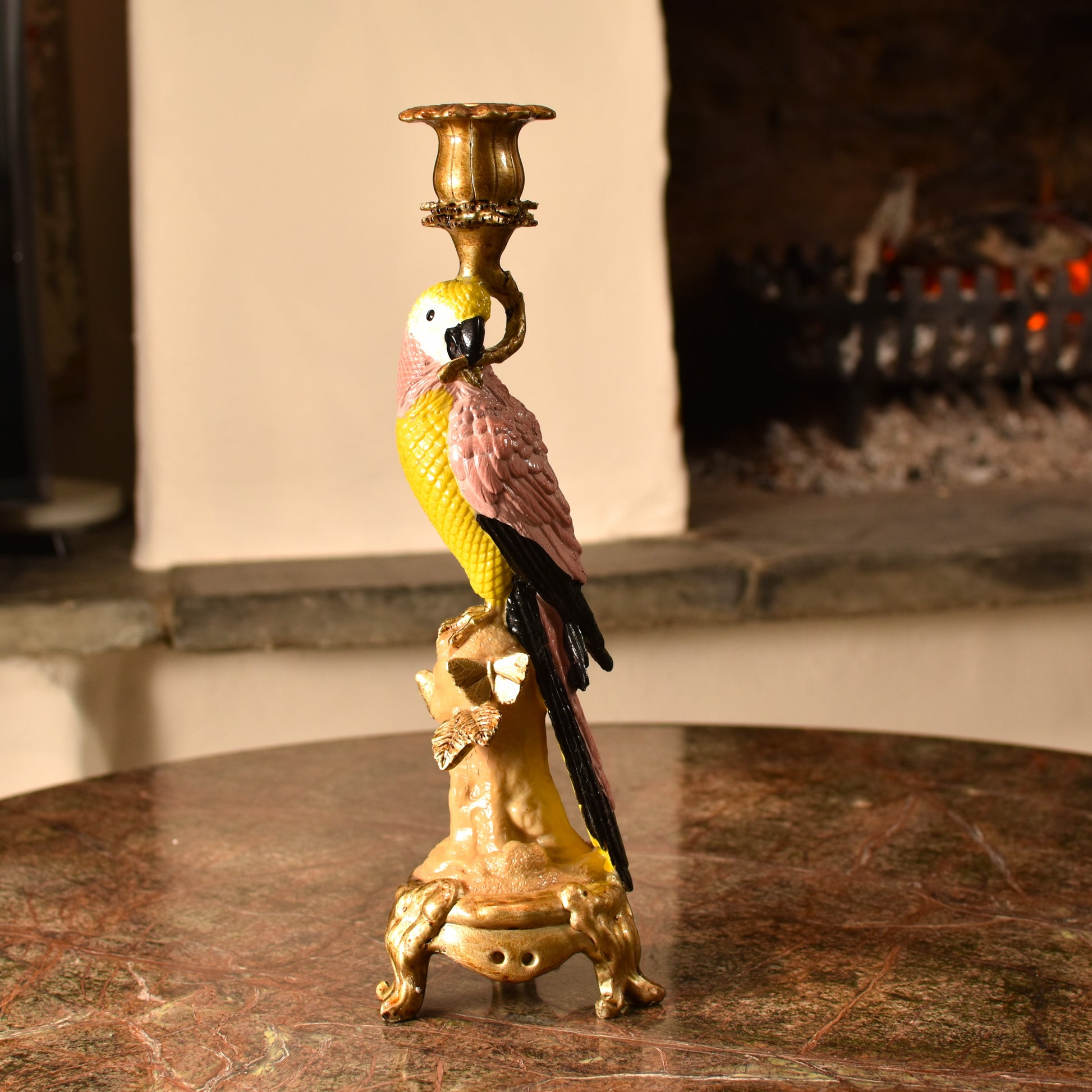 Candle holder shaped like a pink & yellow parrot with a gold base