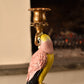 Candle holder shaped like a pink & yellow parrot with a gold base