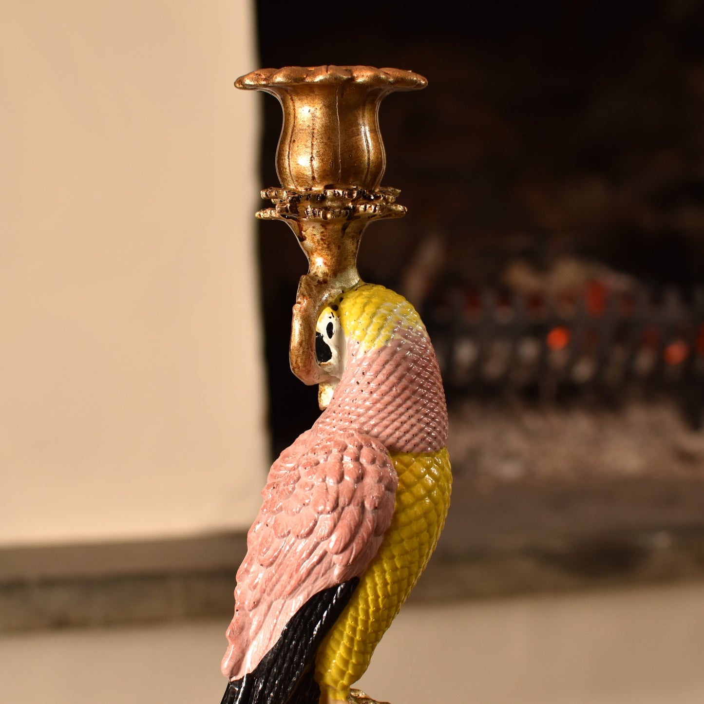 Candle holder shaped like a pink & yellow parrot with a gold base