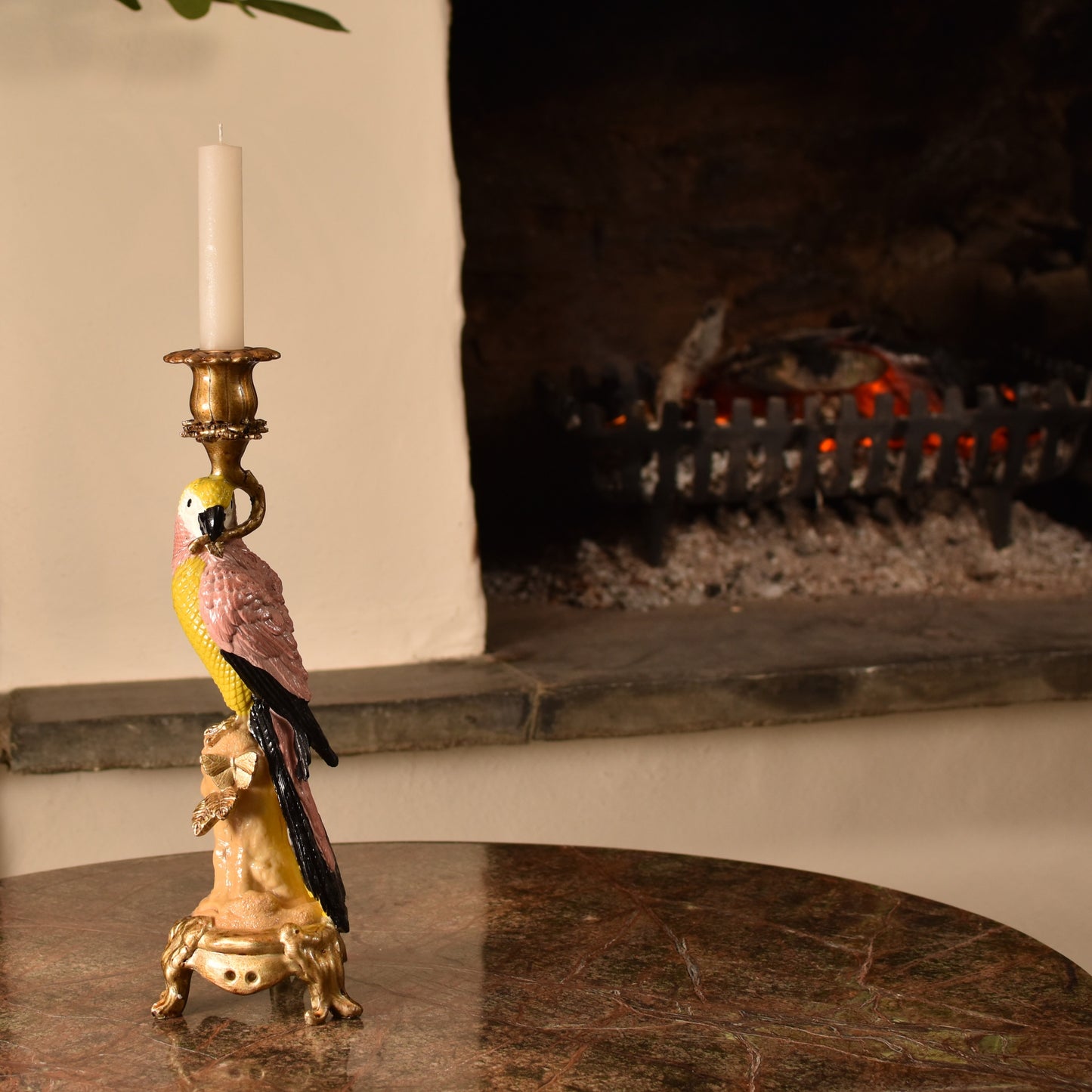 Candle holder shaped like a pink & yellow parrot with a gold base