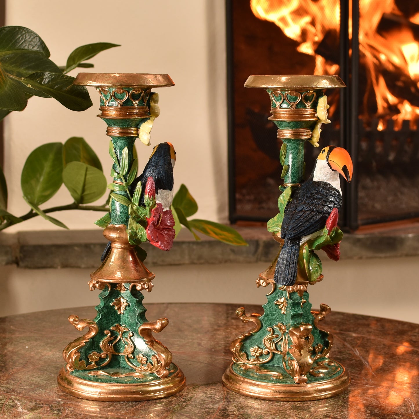 Decorative candle holders with bird designs on a table in front of a fireplace.