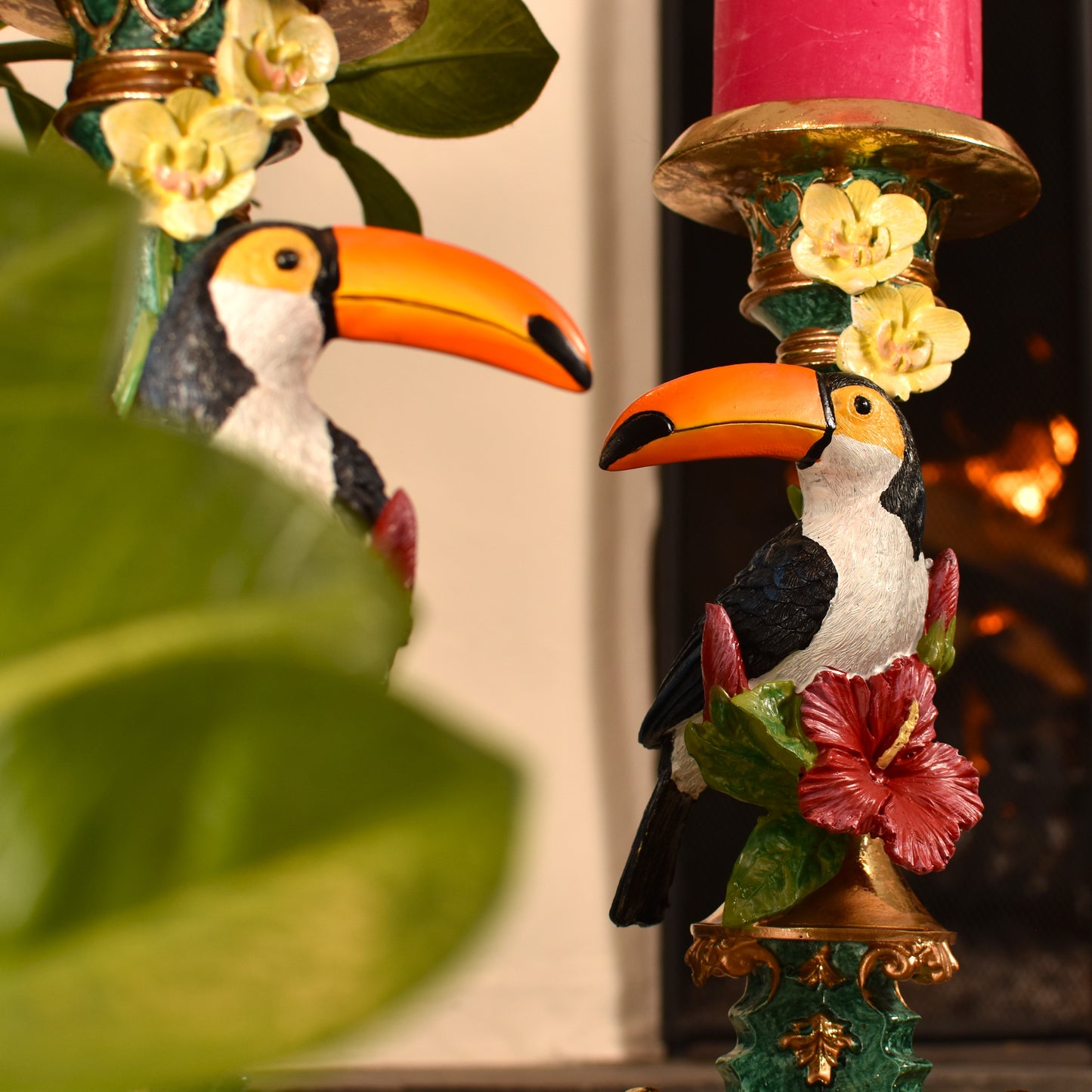 Decorative figurines of toucans with floral elements on a candle holder.