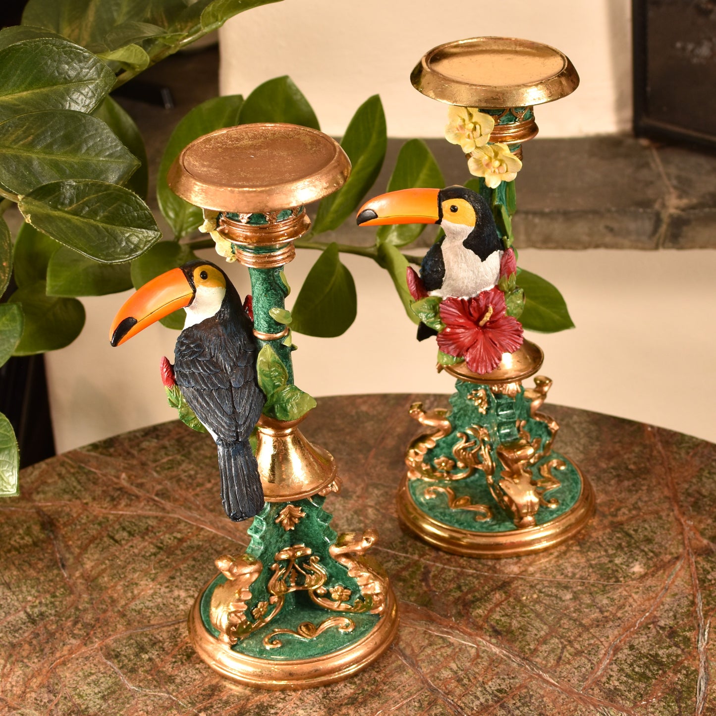 Decorative candle holders with toucan designs on a marble surface.